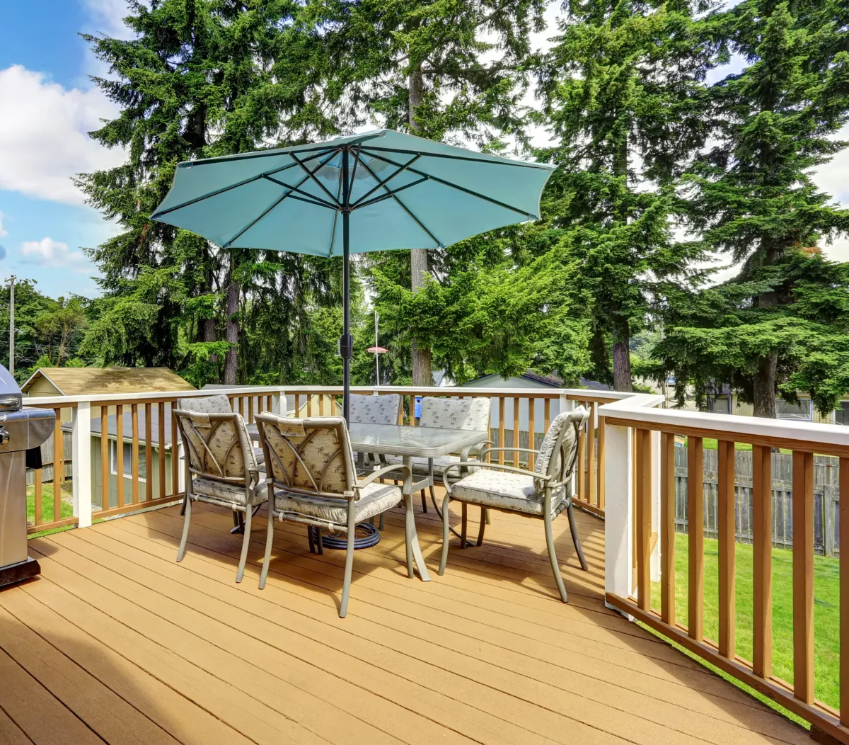 Walkout deck in brown and white trim. Patio table set with umbrella and jacuzzi